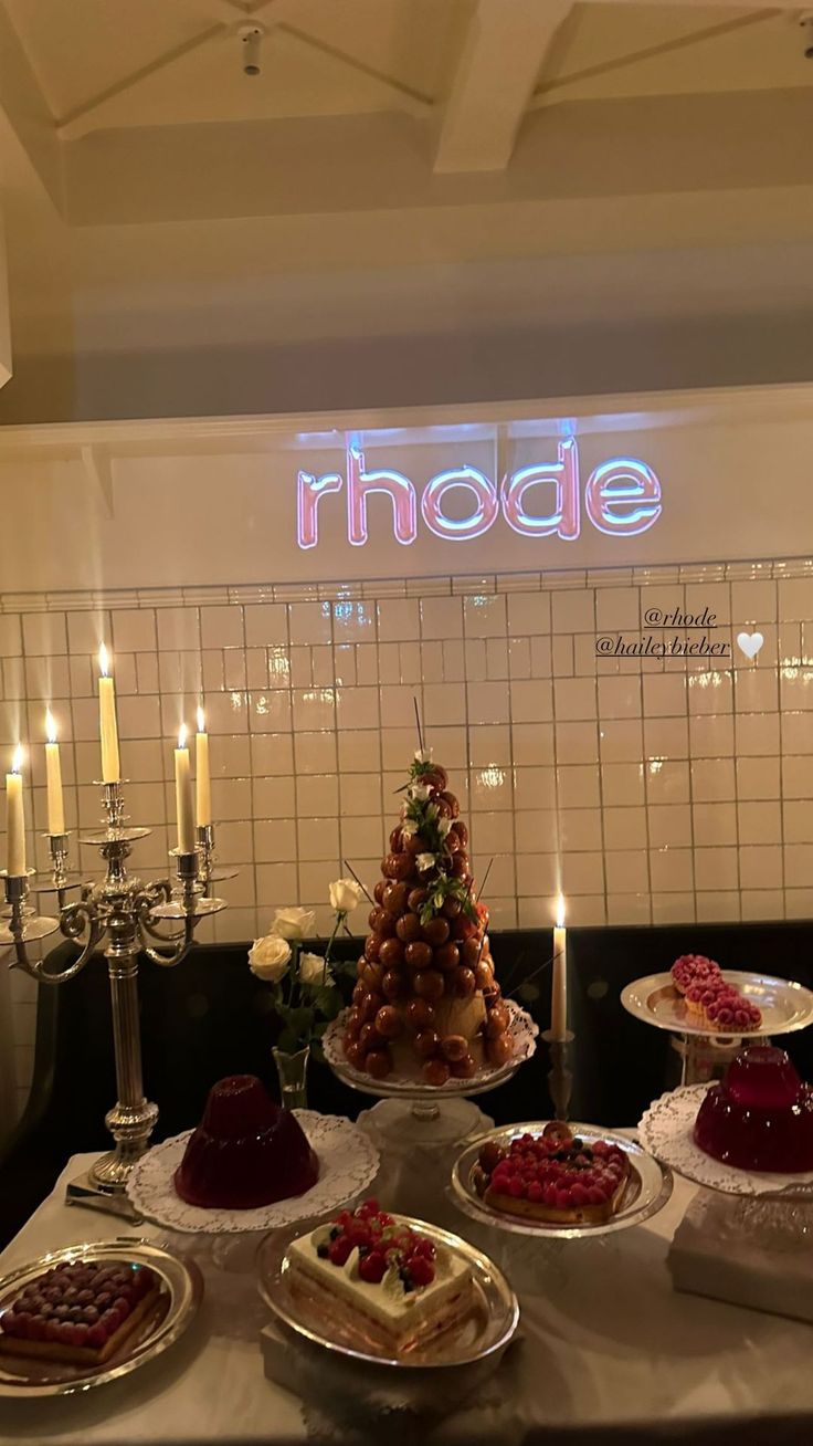 a table topped with cakes and desserts covered in frosting next to lit candles