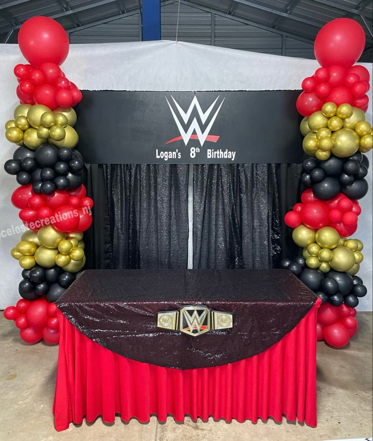 the entrance to an event decorated with balloons and streamers in black, gold and red colors