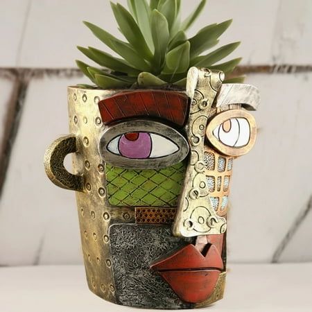 a potted plant with an artistic face painted on it