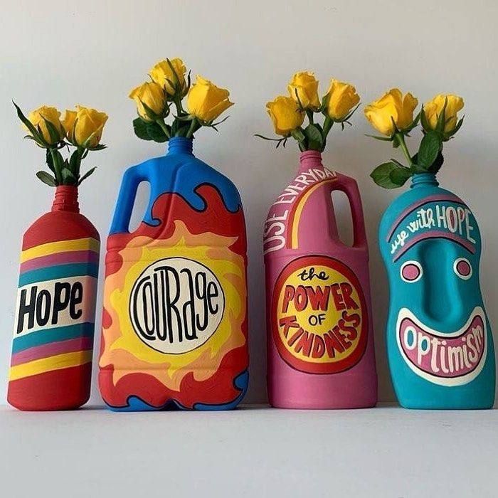 three colorful vases with yellow roses in them