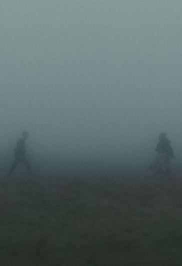 two people are running in the foggy field