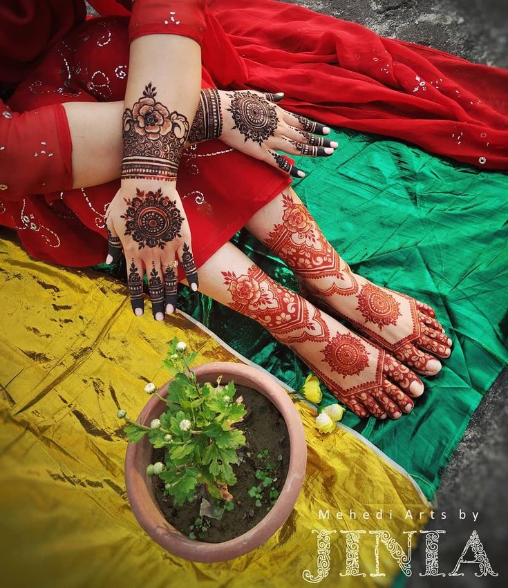 two hands and feet with henna designs on them next to a potted plant