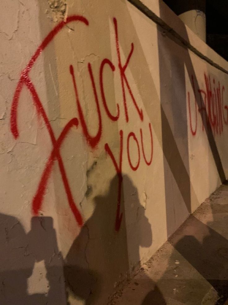 graffiti is spray painted on the side of a white wall with red writing that says luck you