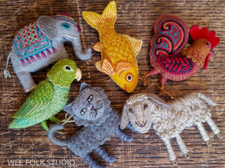 several small knitted animals are sitting on a wooden surface with one cat and the other two birds