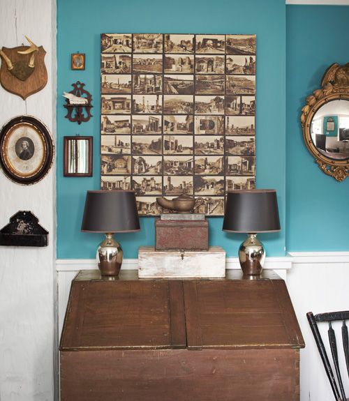 an old desk with two lamps on it in front of a blue wall and mirror