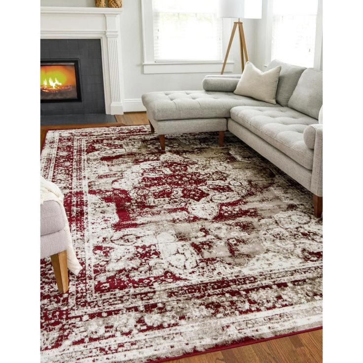 a living room area with a couch, chair and rug on the floor in front of a fire place