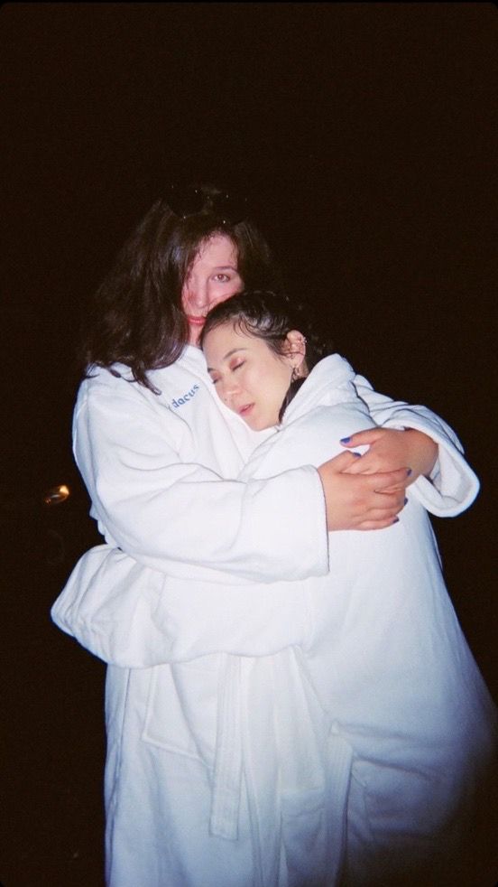 two people hugging each other in the dark with their arms wrapped around one person's shoulders