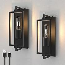 two black wall lights mounted to the side of a white wall