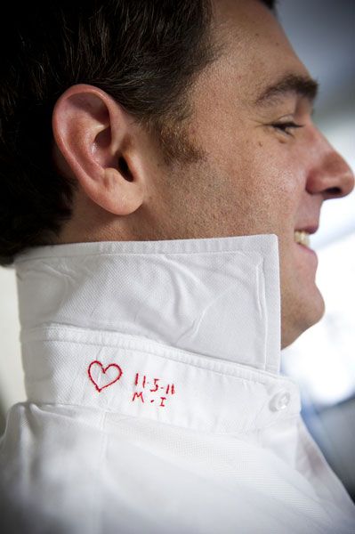 a man wearing a white shirt with a red heart embroidered on it