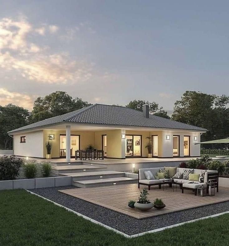 a house that is sitting in the middle of a grass covered yard with chairs and couches