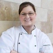 a woman in a chef's coat standing with her arms crossed