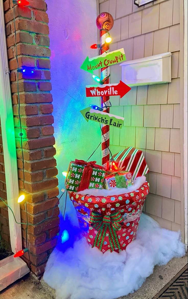 a basket filled with presents sitting in front of a building decorated for the holiday season