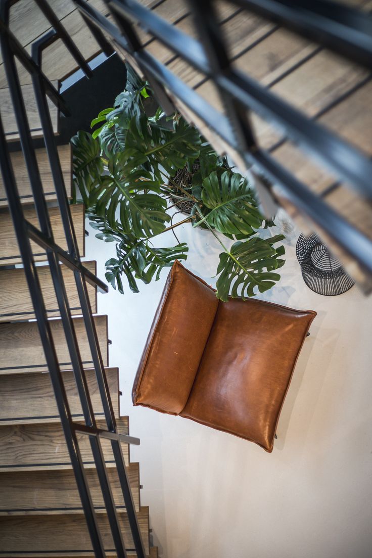 a brown pillow sitting on top of a wooden floor next to a metal handrail