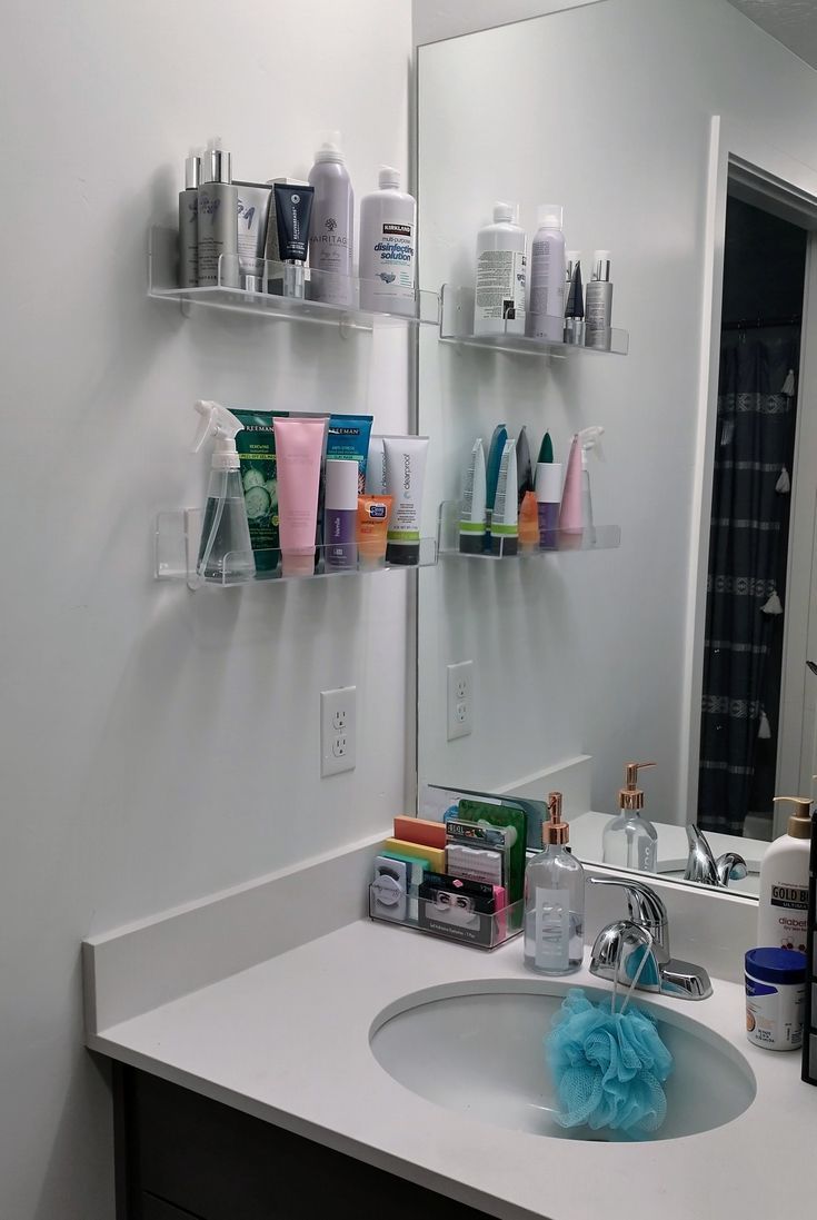 a bathroom sink with lots of personal care products on the shelf above it and in front of the mirror