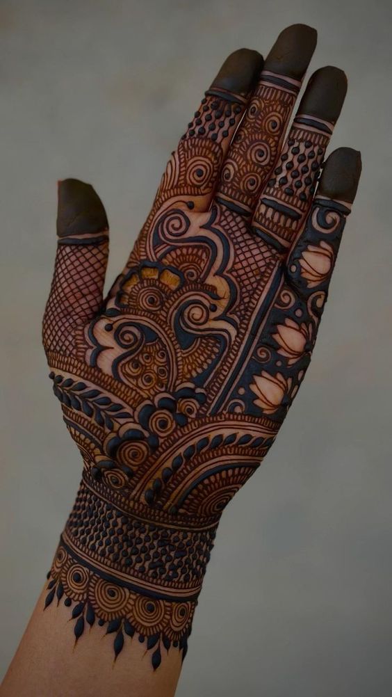 a person's hand with hennap and tattoos on their arm, showing the intricate