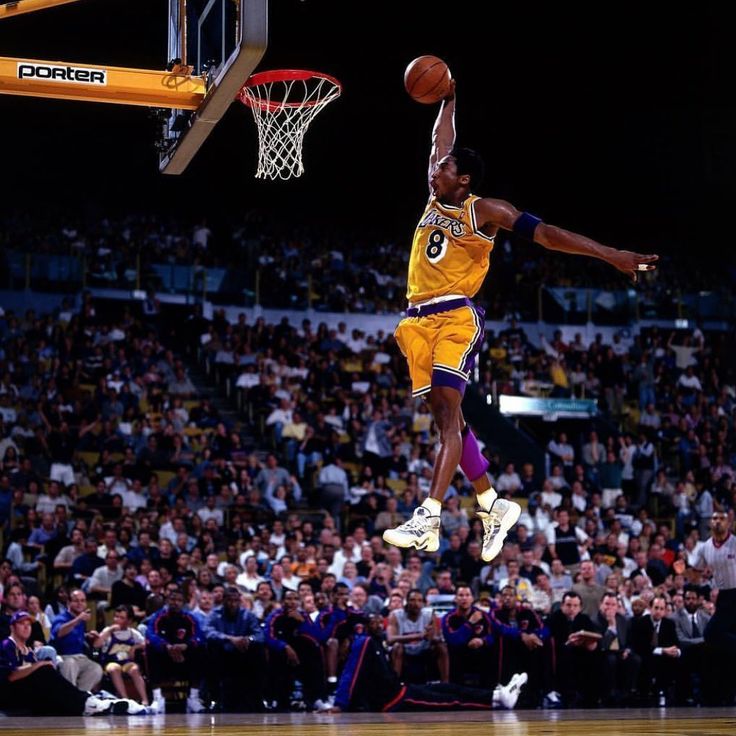 a basketball player jumping up into the air to dunk a ball in front of an audience