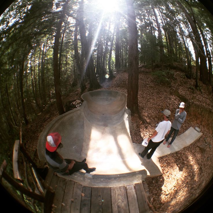 two men are sitting on the edge of a skateboard ramp while another man is taking a photo