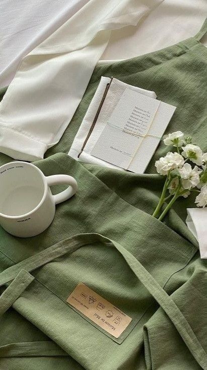 an open book, coffee cup and flowers on a green blanket with white linens