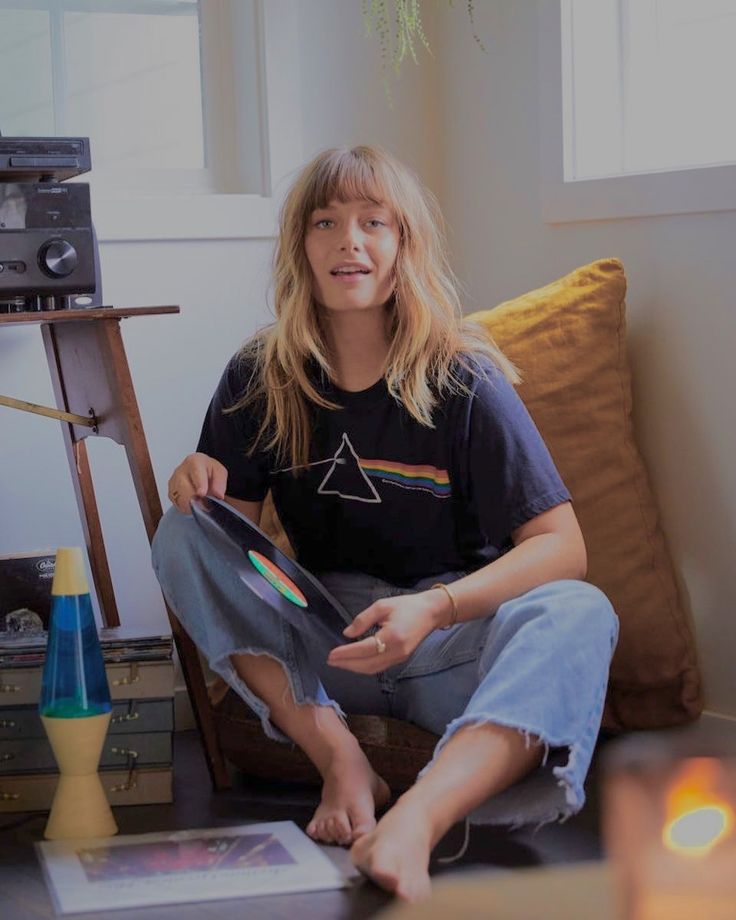 a woman is sitting on the floor with her legs crossed and holding a piece of paper