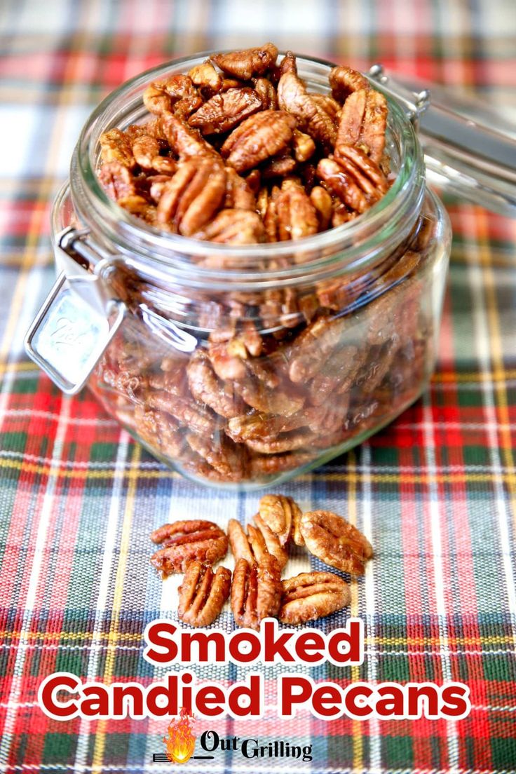 a glass jar filled with candied pecans sitting on top of a plaid table cloth