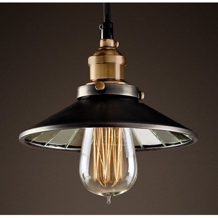 an old fashioned light bulb hanging from a ceiling fixture in a dark, industrial - style room