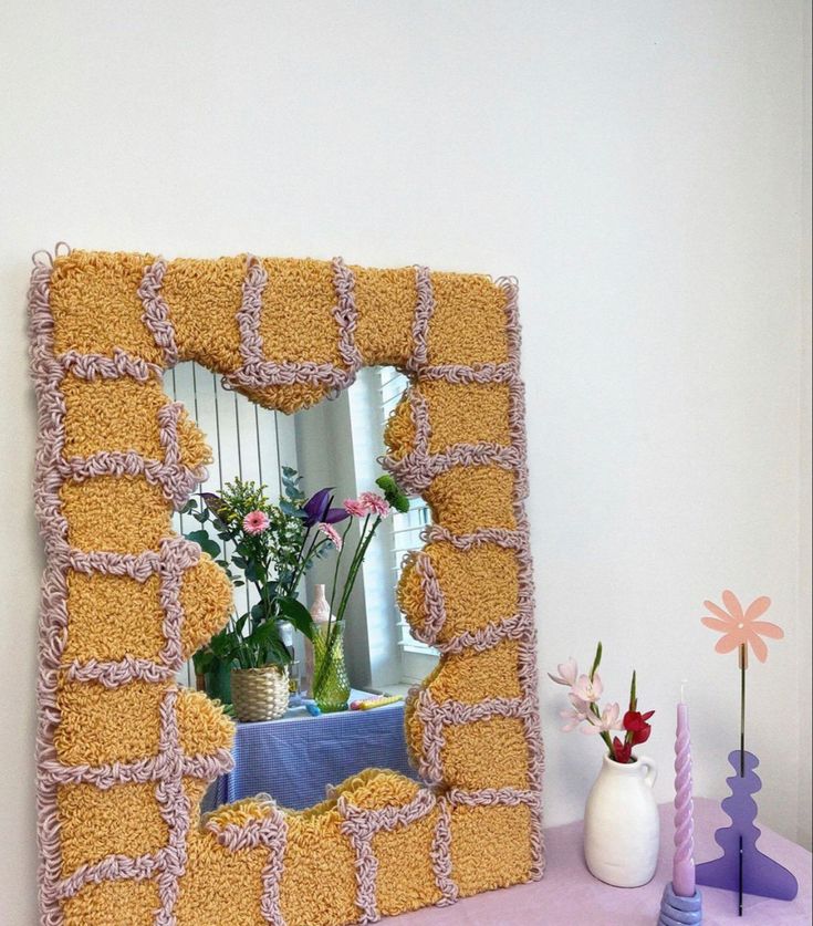 a mirror that is sitting on top of a table next to vases and flowers