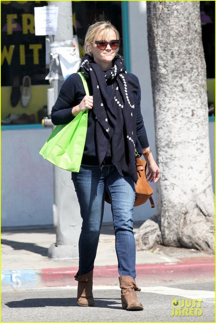 a woman walking down the street carrying a green bag