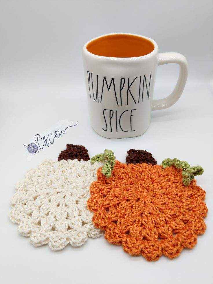 two crocheted pumpkin coasters next to a coffee cup with the words pumpkin spice written on it