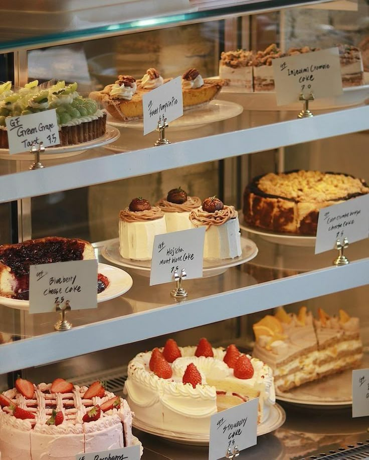 a display case filled with lots of different types of cakes and pies on plates