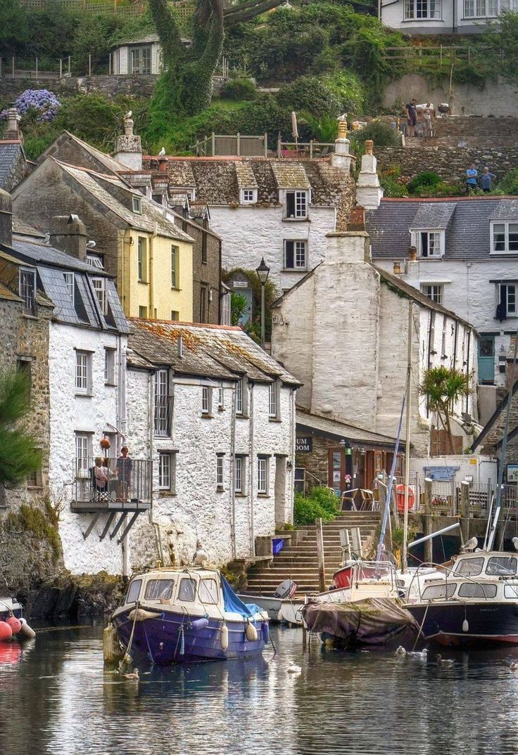 several boats are docked in the water next to houses and buildings on a hill side