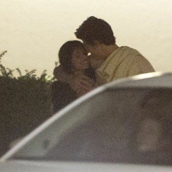 two people are kissing in front of a car