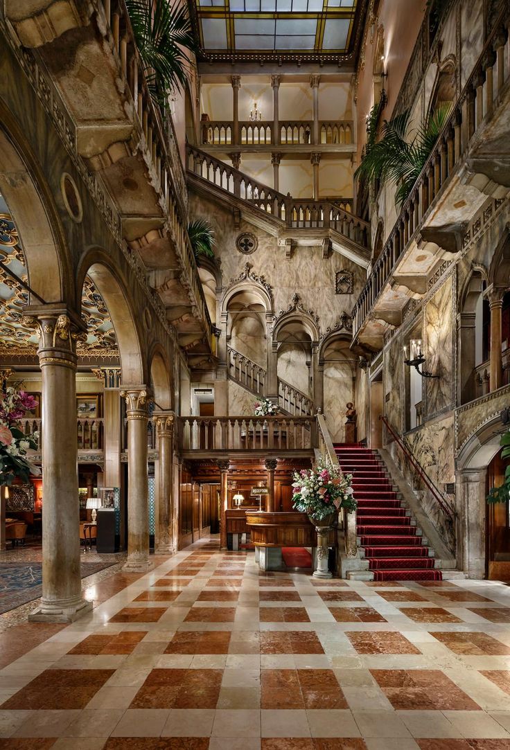 an ornate lobby with stairs and potted plants