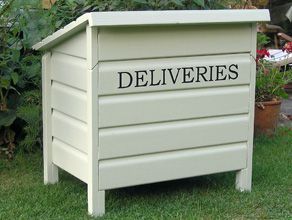 a white box sitting in the grass near some bushes and flowers with words written on it