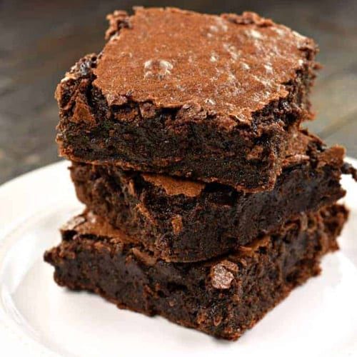 three brownies stacked on top of each other on a white plate with chocolate chips