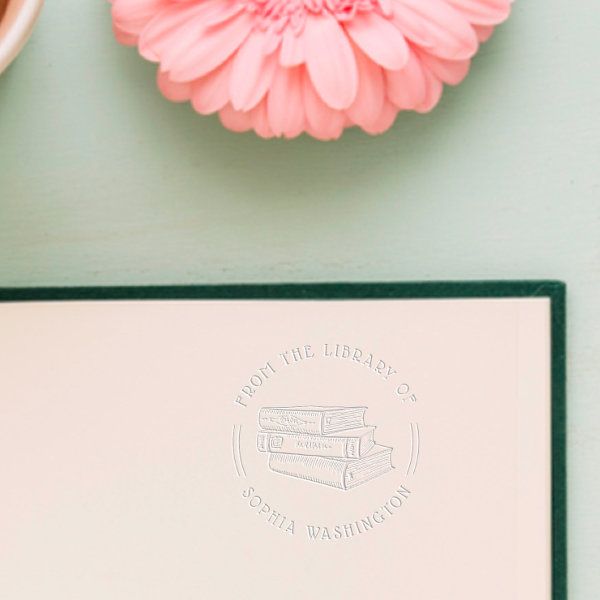 a pink flower sitting on top of a desk next to a book