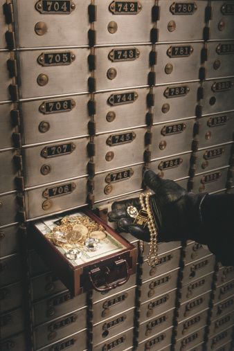 a person's hand reaching for a briefcase in front of mailboxes