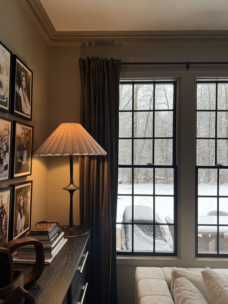 a living room filled with furniture and a lamp next to a window covered in snow