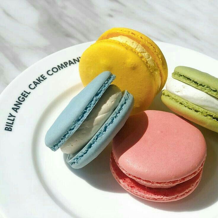 three different colored macaroons on a white plate