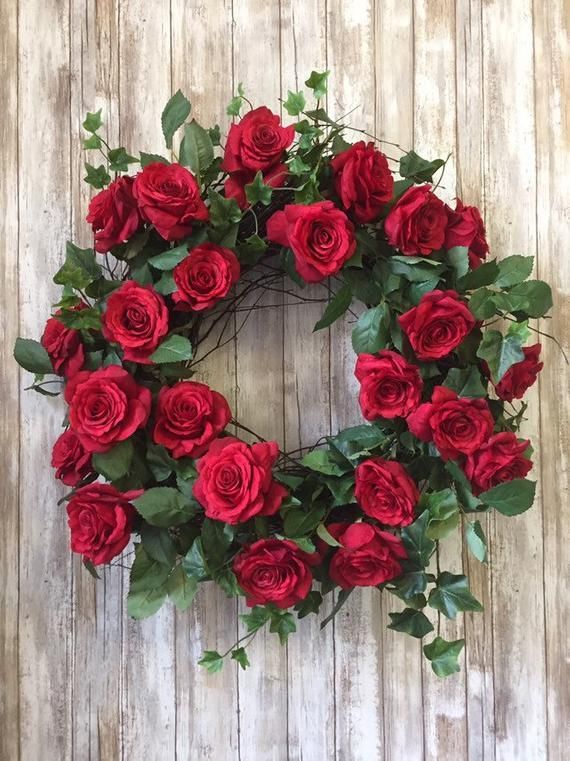 a wreath with red roses and green leaves on a wooden background, ready to be used as a decoration