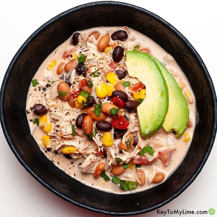 a black bowl filled with beans, avocado and other foods on top of it