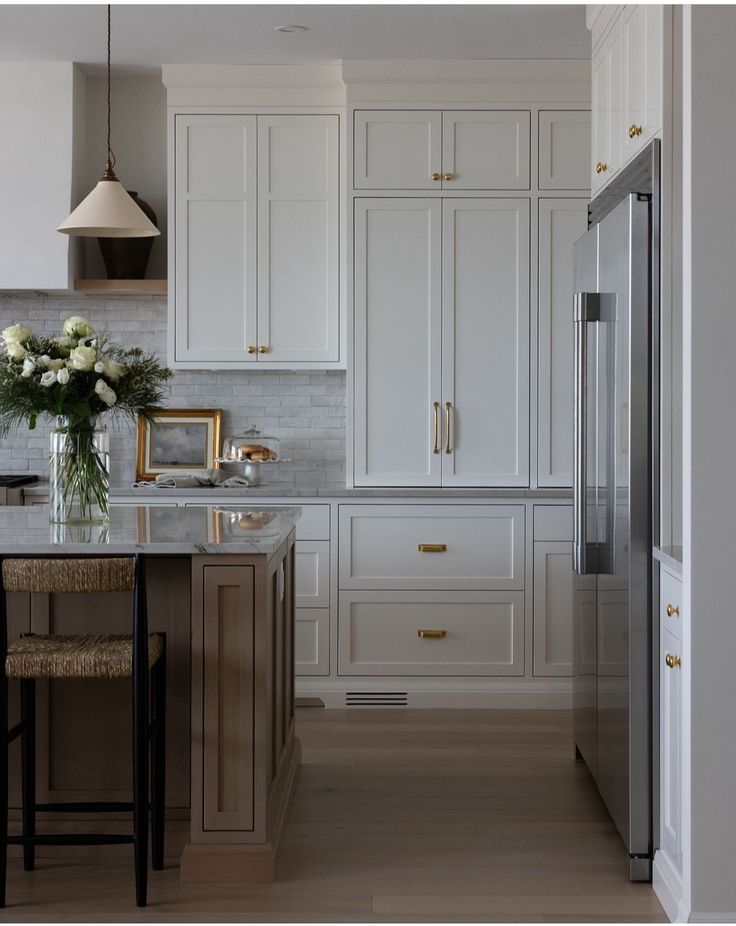 a kitchen with white cabinets and marble counter tops