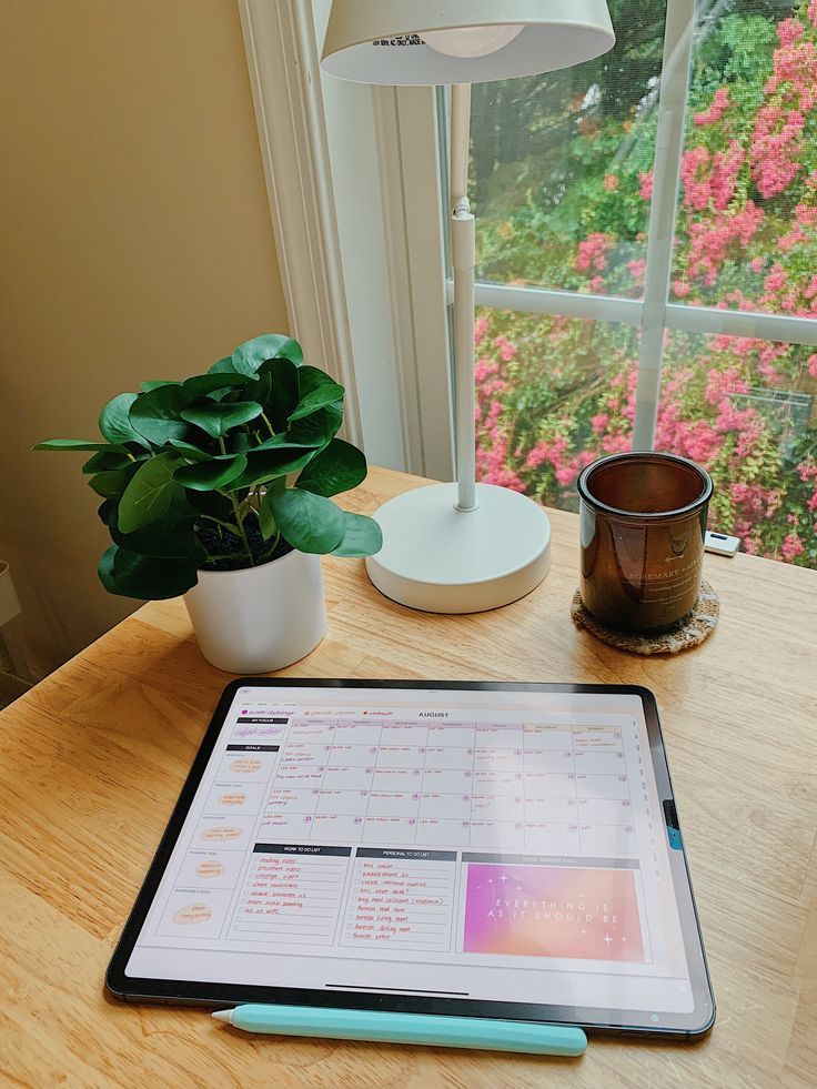 a tablet computer sitting on top of a wooden table next to a potted plant