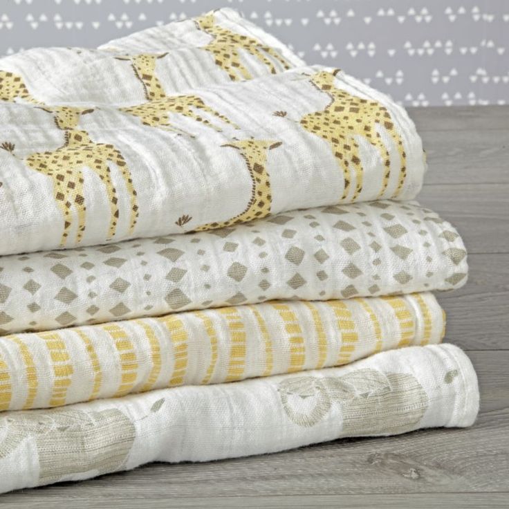 four pieces of white and yellow quilts stacked on top of each other in front of a wall