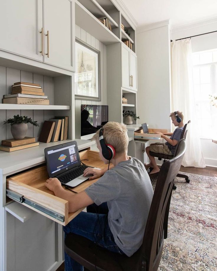 two people sitting at a desk with laptops and headphones