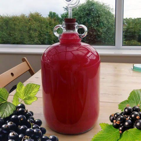 a red jug sitting on top of a table next to grapes