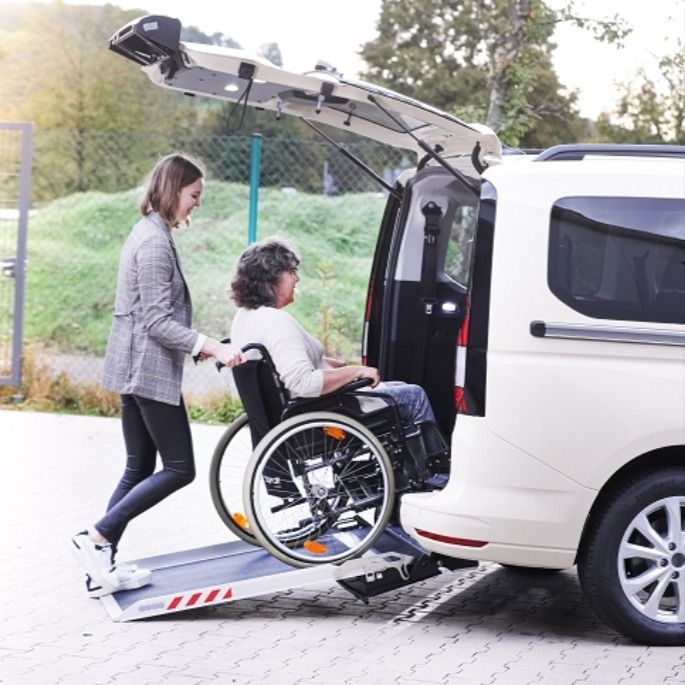 a woman pushing a wheelchair into a van