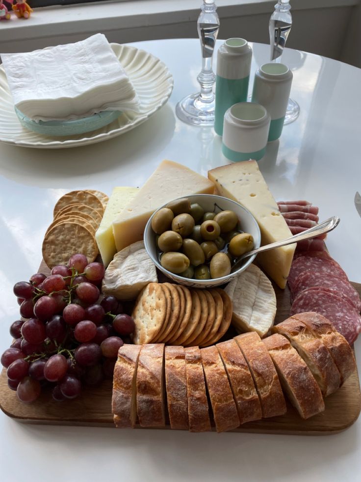 an assortment of cheeses, crackers and olives on a platter