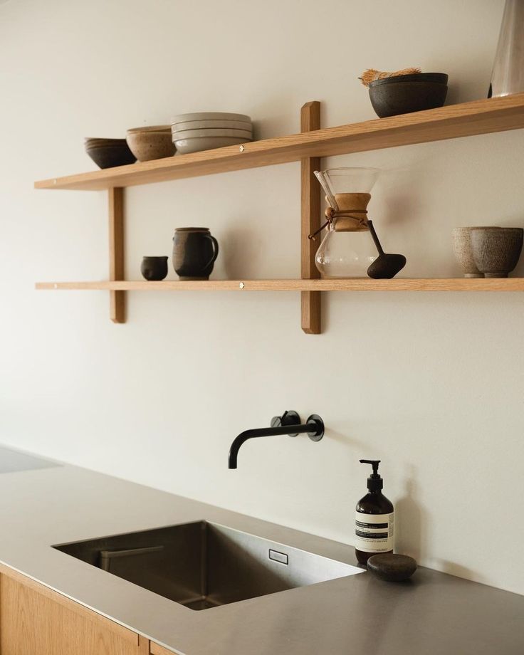 a kitchen with wooden shelves above the sink