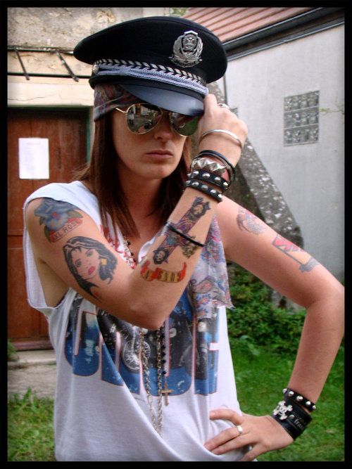 a woman with tattoos on her arm wearing a police hat and holding his hand up to the side