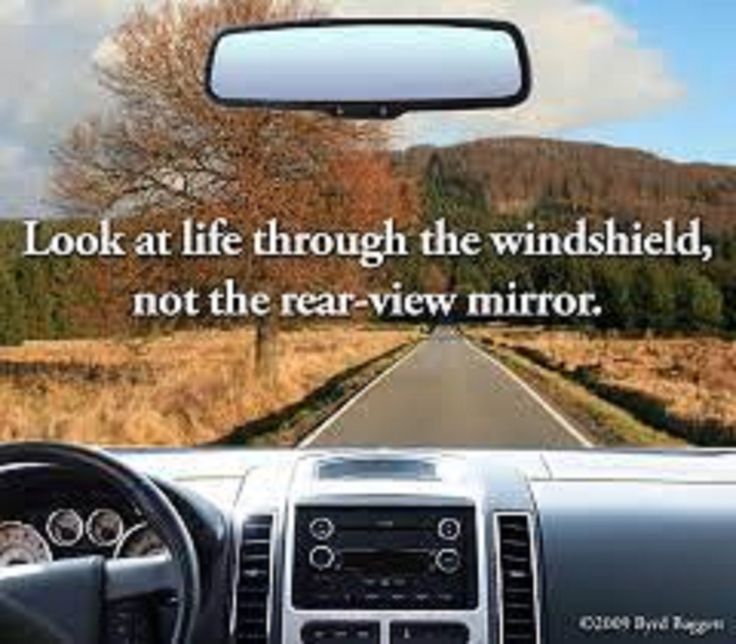 a car driving down a country road with a quote on the front window that reads, look at life through the windshield, not the rear view mirror